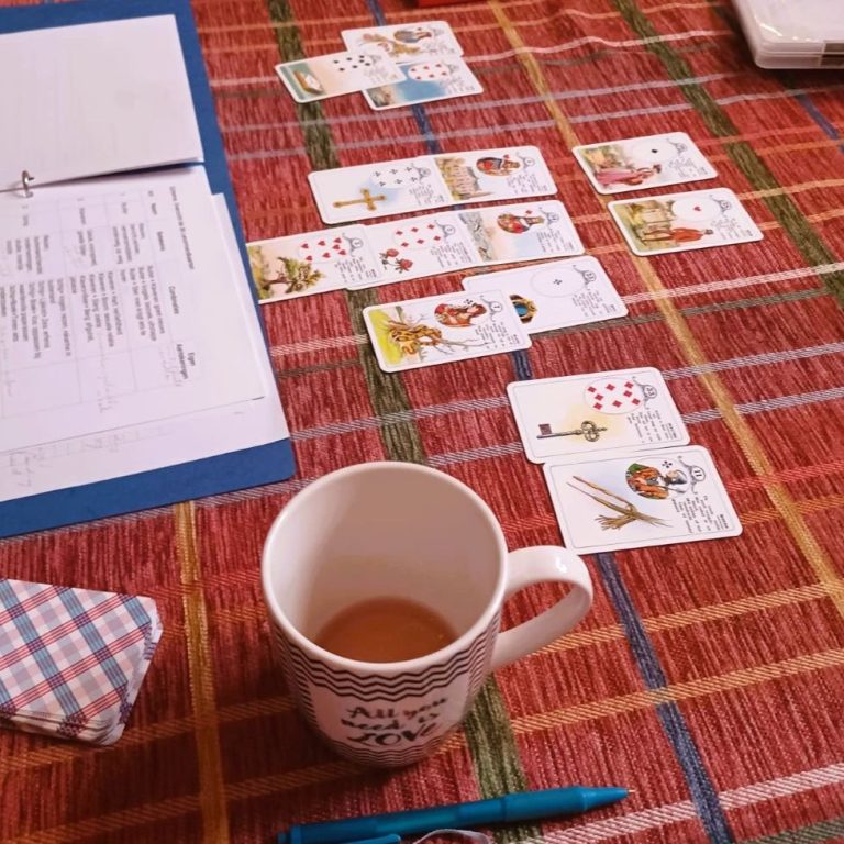 Kaartspel op een tafel met een kop thee en enkele notities ernaast.