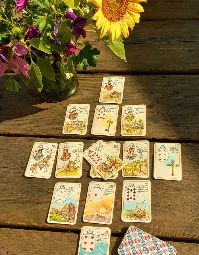 Kaartspel op een houten tafel met een vaas zonnebloemen en kleurrijke bloemen.