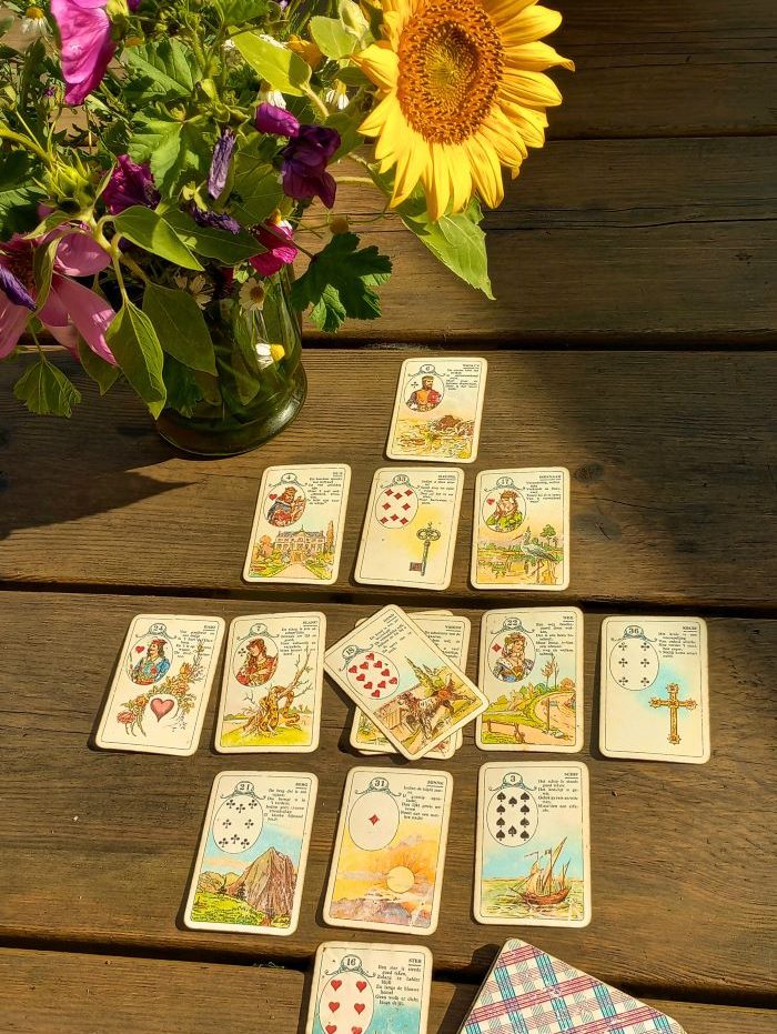Speelkaarten op een houten tafel met een zonnebloem en bloemen in een vaas.